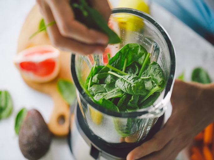 Man cooking healthy detox smoothie with fresh fruits and green spinach. Lifestyle detox concept